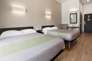 A hotel room with two beds, a bedside table, a chair, a desk, and a mirror on the wall. - 2 Queen Beds|Mobility Accessible (Corpus Christi TX)