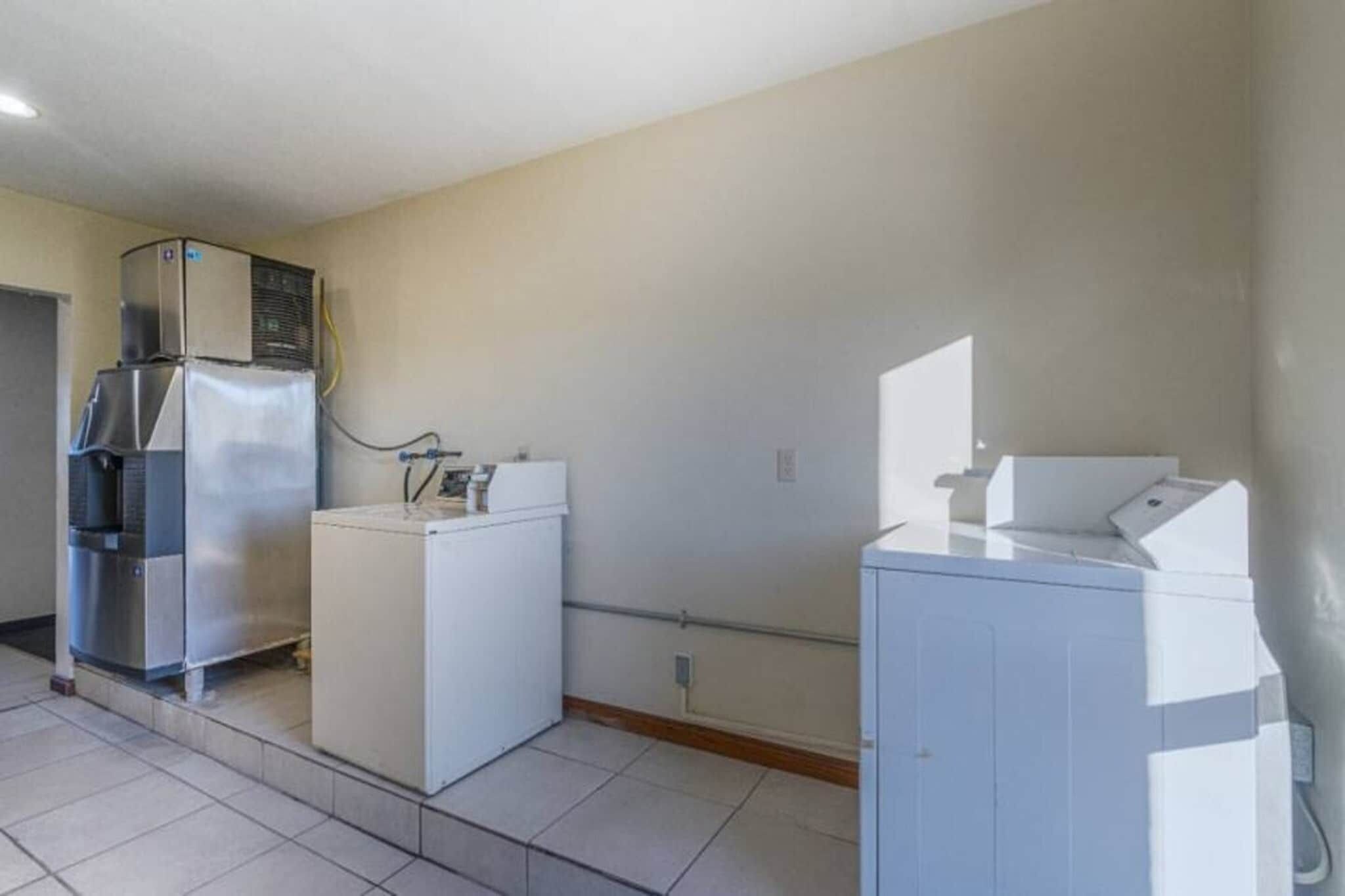 A laundry room with a refrigerator, washing machine, and dryer.