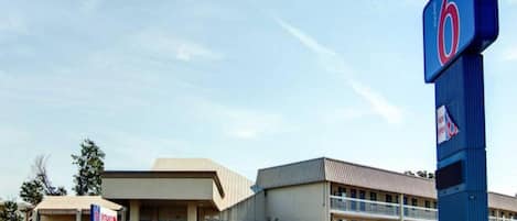 A motel with a prominent '6' sign, a parking lot, and a building with a flat roof.