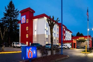 A motel with a red and white exterior, a parking lot with several cars, and a sign indicating the motel's name. - 1 Queen Bed|Mobil Access|Nsmk|Kitchen (Belmont)