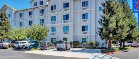 A multi-story hotel with a parking lot and several vehicles.