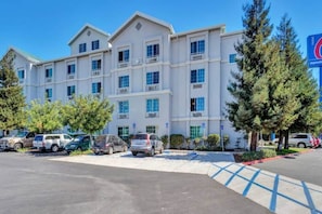 A multi-story hotel with a parking lot and several vehicles. - 1 Queen Bed|Mobil Access|Nsmk|Kitchen (Belmont)