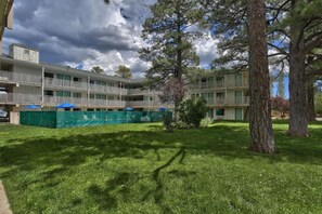 A multi-story building with balconies, surrounded by a well-maintained lawn and trees. - 2 Full Beds | Micfridge (Flagstaff AZ)