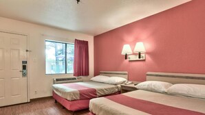 Habitación de hotel con dos camas, una ventana con cortinas, una lámpara fijada a la pared y una puerta con cerradura.