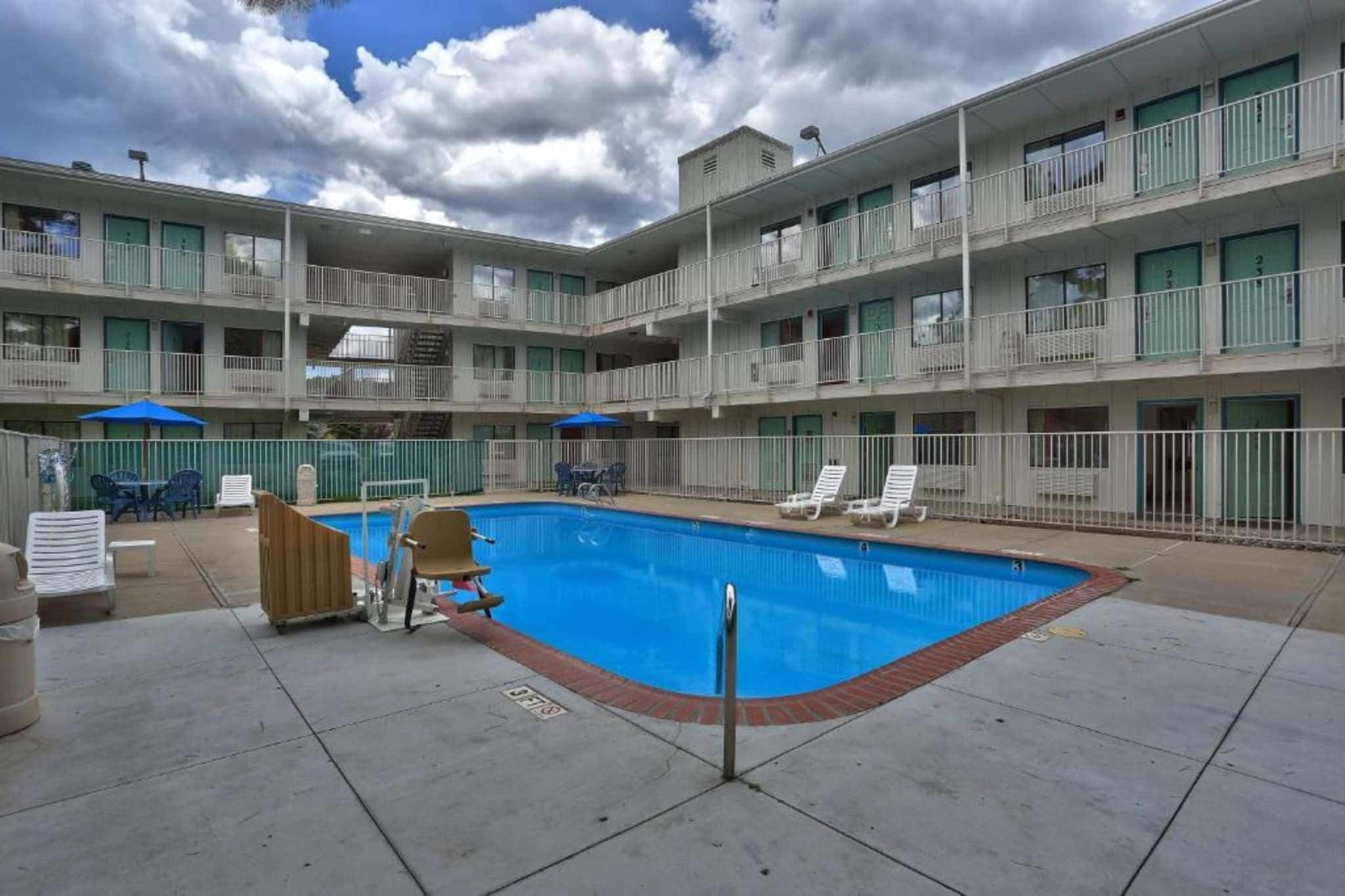 A multi-story hotel with a swimming pool, outdoor seating, and balconies.