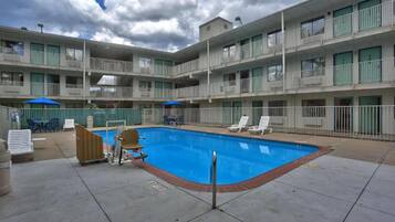 A multi-story hotel with a swimming pool, outdoor seating, and balconies.