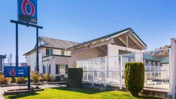 Un motel con entrada despejada, una zona de estar techada al aire libre y un césped bien cuidado.