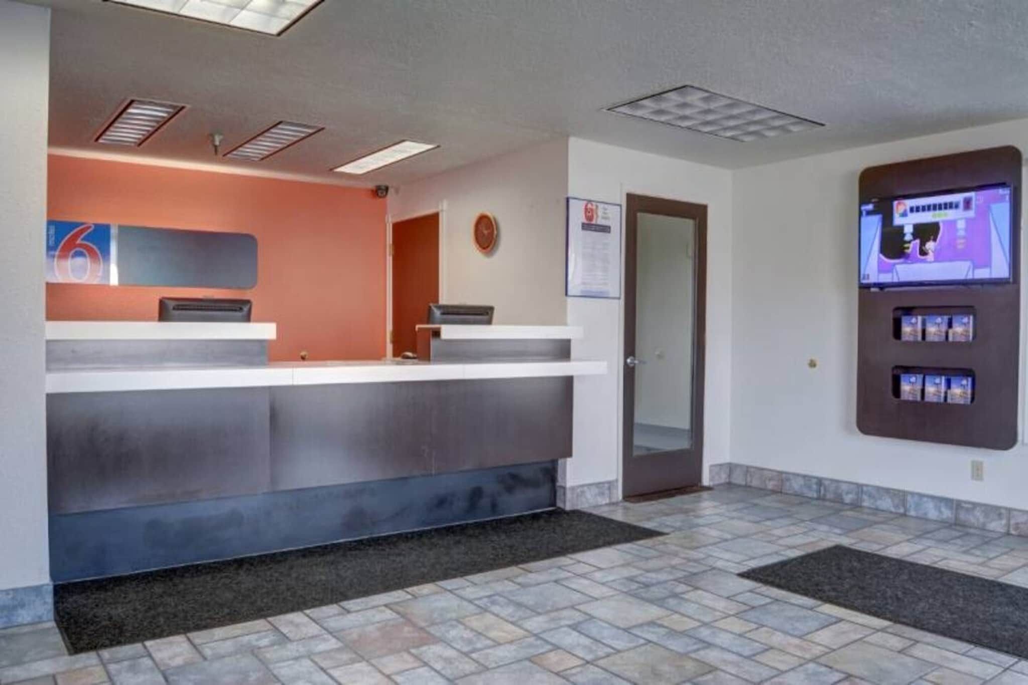 A reception area with a counter, a clock, a door, and a vending machine.