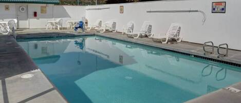 Una piscina con lettini e una postazione di salvataggio.