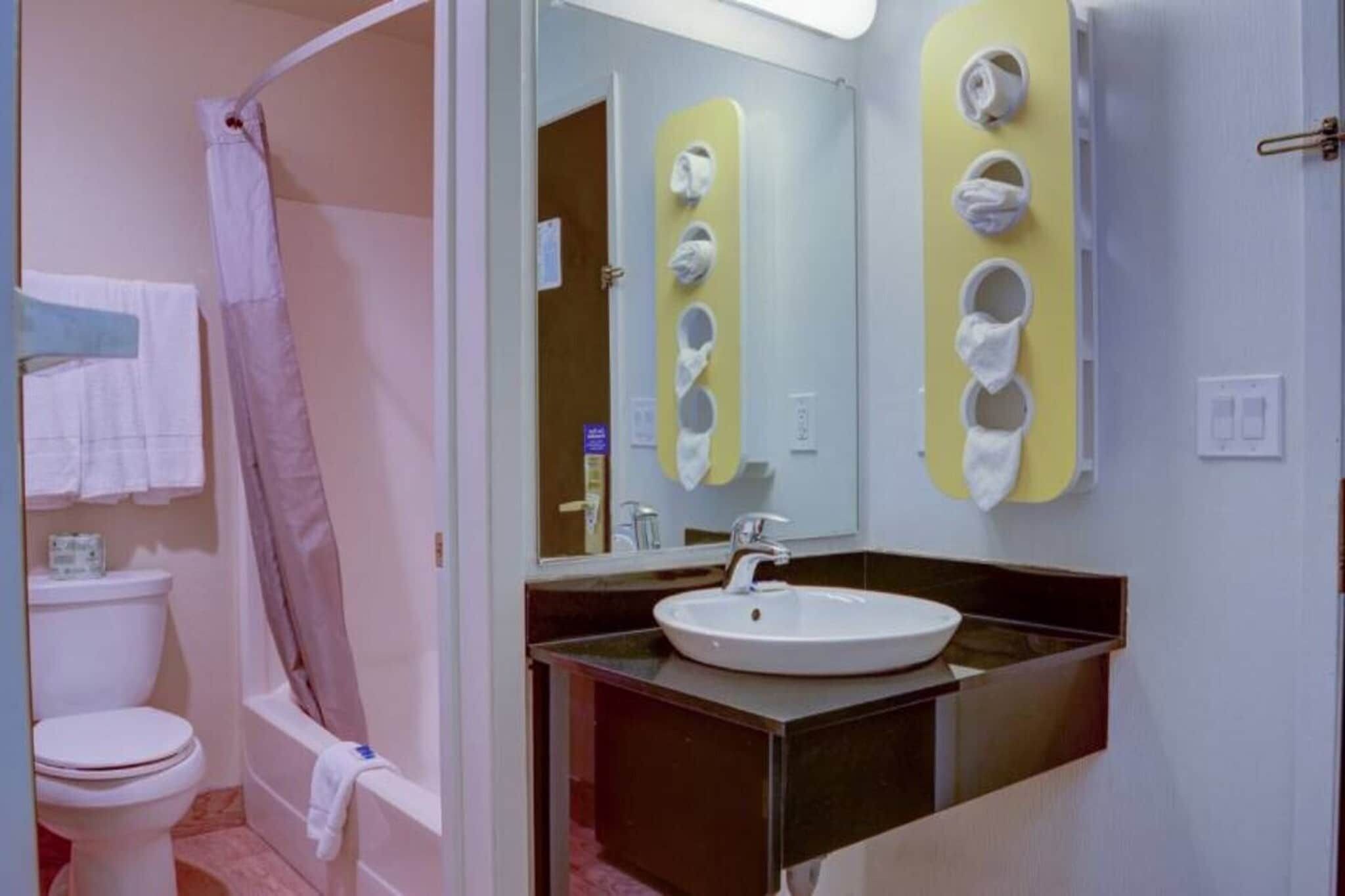 Ein Badezimmer mit Toilette, Waschbecken, Spiegel und Duschbereich.