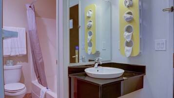 Ein Badezimmer mit Toilette, Waschbecken, Spiegel und Duschbereich.