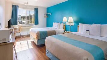 Habitación de hotel con dos camas, un escritorio y una ventana con cortinas.