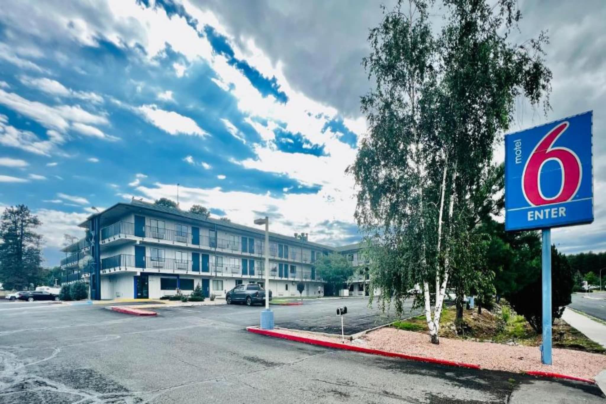 A motel with a large building, a parking lot, and a sign indicating the entrance.