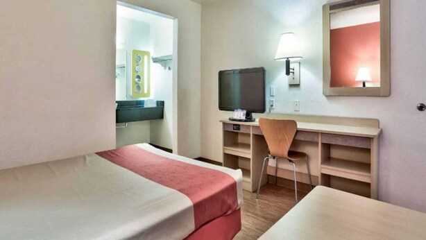 A hotel room with two beds, a desk with a chair, a television, and a mirror. - 1 Queen Bed | Flagstaff AZ (Flagstaff AZ)