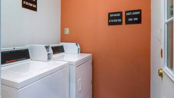A laundry area with two front-loading washers and dryers, soap available at the front desk, and guest laundry service from 8 AM to 9 PM.