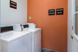 A laundry area with two front-loading washers and dryers, soap available at the front desk, and guest laundry service from 8 AM to 9 PM.