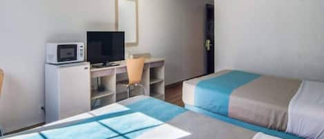 Una camera d'albergo con due letti, una scrivania con computer e televisore, e un forno a microonde.