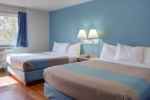 Habitación de hotel con dos camas, una ventana con cortinas, un equipo de aire acondicionado y una mesita de noche con lámpara.