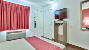 Une chambre d’hôtel avec un lit, une télévision, une porte et un miroir.