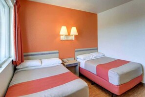 Een hotelkamer met twee bedden, een nachtkastje en een raam met gordijnen.