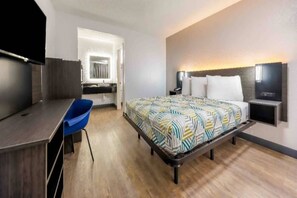 A hotel room with a bed, a desk, a chair, a TV, and a bathroom. - 1 King Bed|Smoking|Fort Worth (Fort Worth TX)