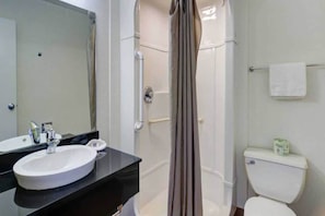Een badkamer met een wit wastafelmeubel, spiegel, douchecabine en toilet.