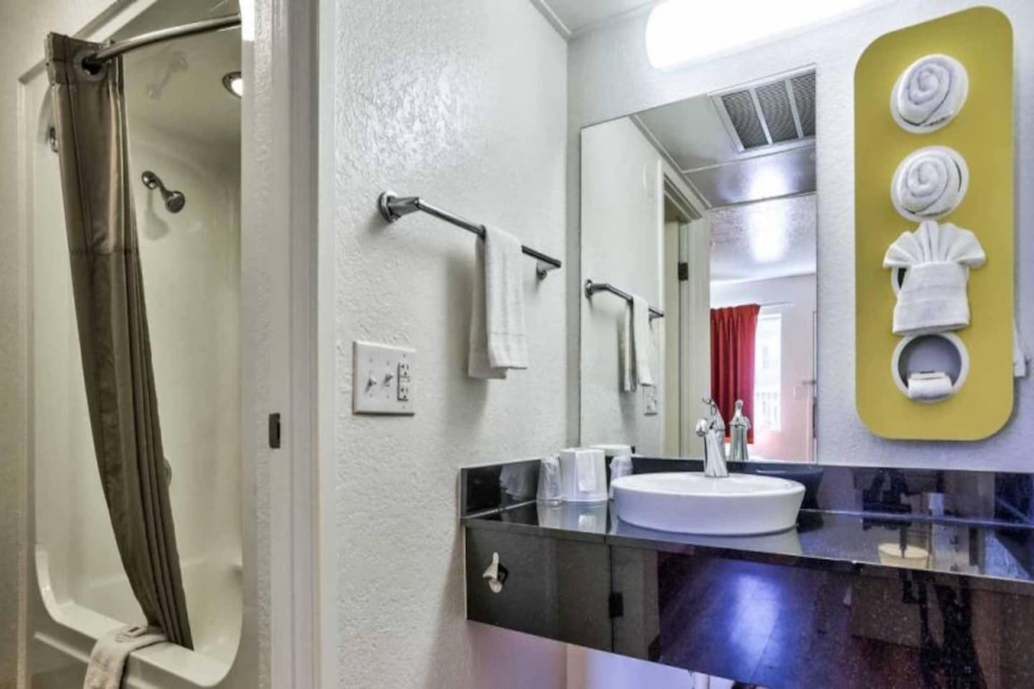 Un baño con ducha, lavabo y espejo.