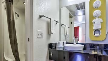 Un baño con ducha, lavabo y espejo.