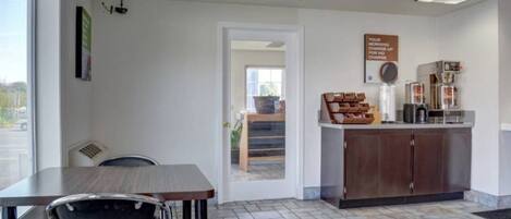 A clean, modern cafe interior with a seating area, a counter with coffee-making equipment, and a sign indicating a morning charge.