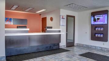 Zona de recepción con mostrador, un reloj, una puerta y una máquina expendedora.