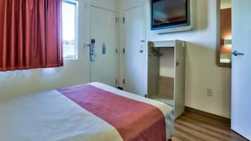 A hotel room with a bed, a television, a wardrobe, and a shower area.