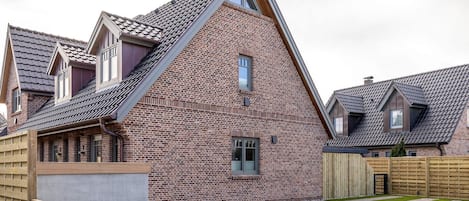 A residential building with a brick facade, a sloped roof, and a small window.