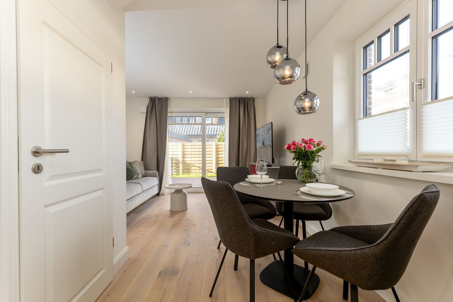 A dining area with a round table, two chairs, and a vase of flowers.