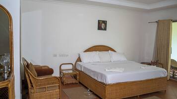 A room with a large bed, a chair, a small table, and a mirror.