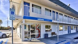 Un motel de dos pisos con un letrero de 'welcome', estacionamiento accesible para discapacitados y una entrada accesible para vehículos utilitarios.