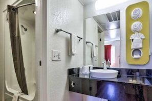 Un baño con ducha, lavabo y espejo.