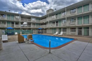 Ein mehrstöckiges Hotel mit Schwimmbad, Sitzgelegenheiten im Freien und Balkonen.