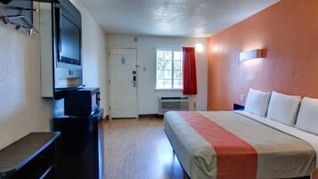 A hotel room with a bed, a desk, a television, and a window with curtains.