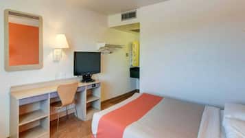 Habitació d'hotel amb un llit, un escriptori, una cadira, una televisió i un aire condicionat fixat a la paret.
