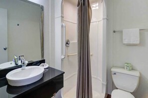 Een badkamer met een wit wastafelmeubel, spiegel, douchecabine en toilet.