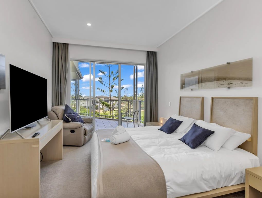 Ein Hotelzimmer mit Bett, Fernseher, Sofa und einem Balkon mit Blick.