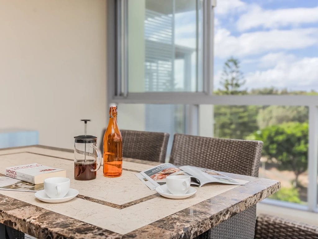 Een tafel met een koffiezetapparaat, een fles en een tijdschrift.