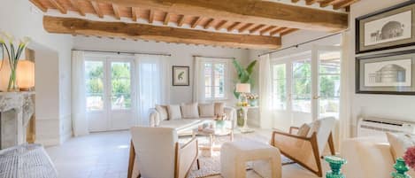 Un vaste salon doté d’un haut plafond en bois, d’une cheminée et offrant une vue sur l’extérieur.