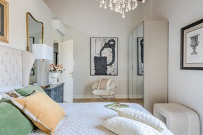 Ein Schlafzimmer mit einem Bett, einem Sessel, einer Kommode und Bildern an den Wänden.