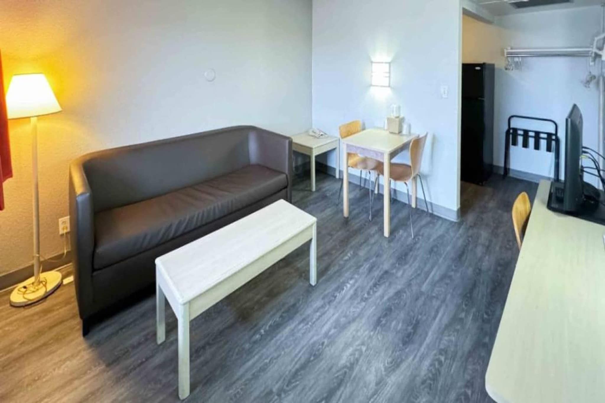 Een moderne woonkamer met een bank, een klein tafeltje en een eethoek met stoelen.