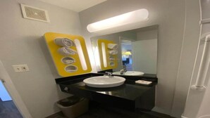 Casa de banho com duas pias, espelho e um contentor de lixo.