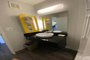 Een badkamer met twee wasbakken, een spiegel en een prullenbak.
