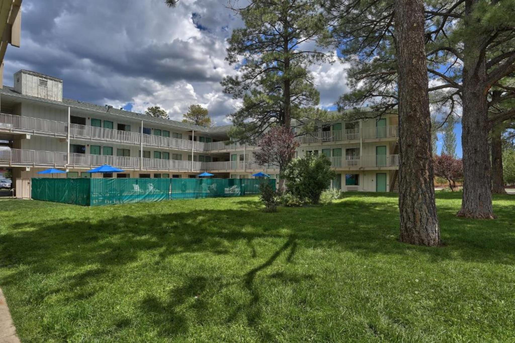 A multi-story building with balconies, surrounded by a well-maintained lawn and trees.