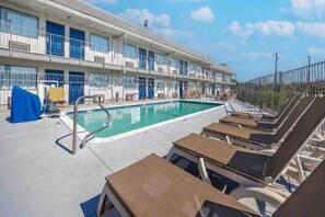 Ein Hotel mit Schwimmbad, Liegestühlen und einem umzäunten Bereich.