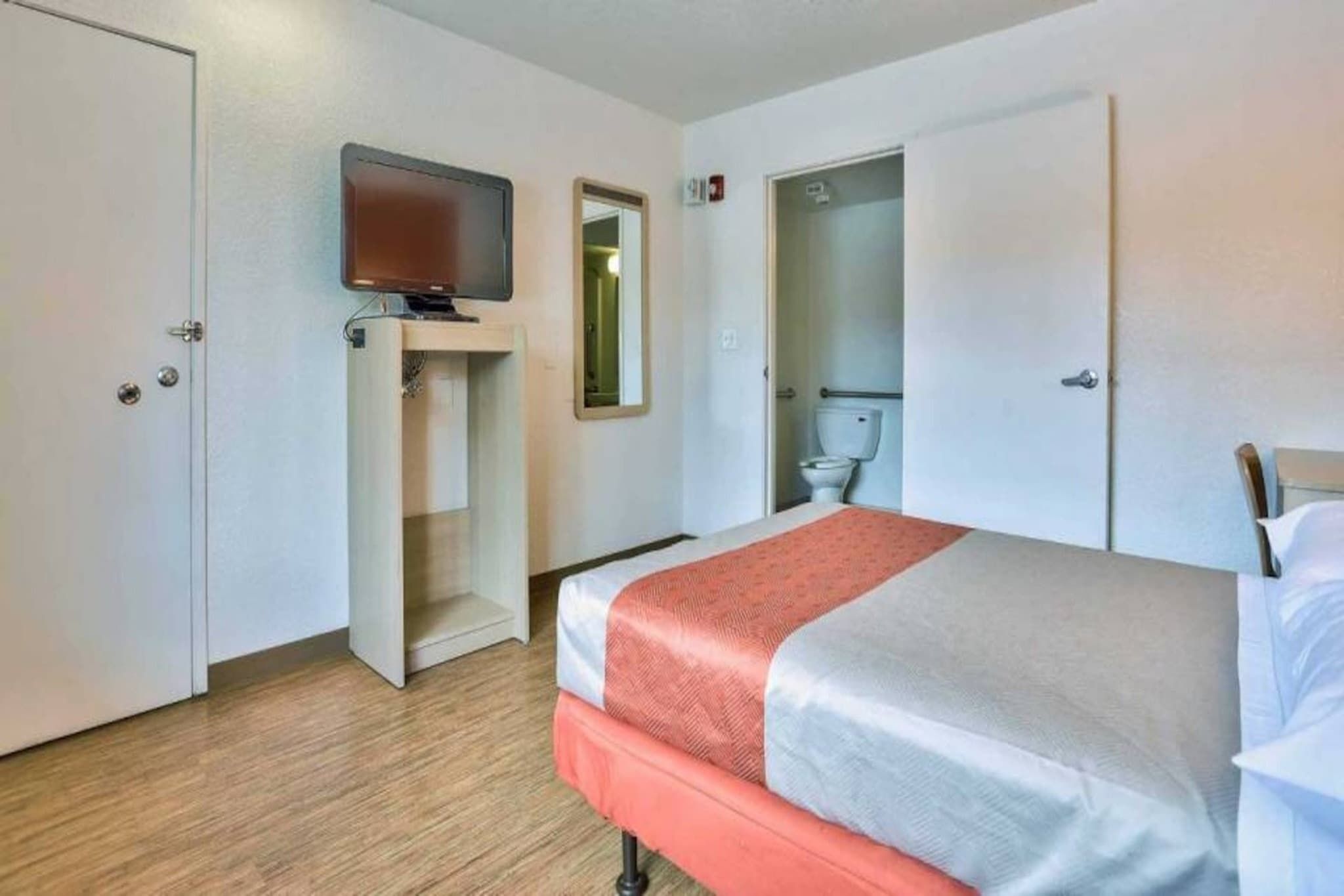 A hotel room with a bed, a television, a wardrobe, and a bathroom.